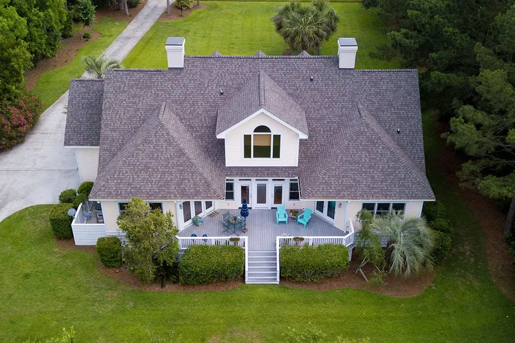 Aerial view of a white house with a broad roof and covered porch